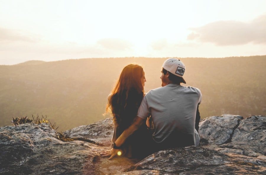 5 Impressive Date Ideas For Those Working Opposite Shifts ​- Man and Women sitting on rocks watching sun rise - The Other Shift