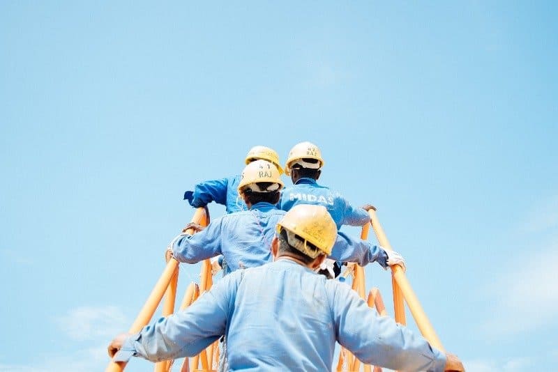 People wearing yellow construction hats climbing ladder