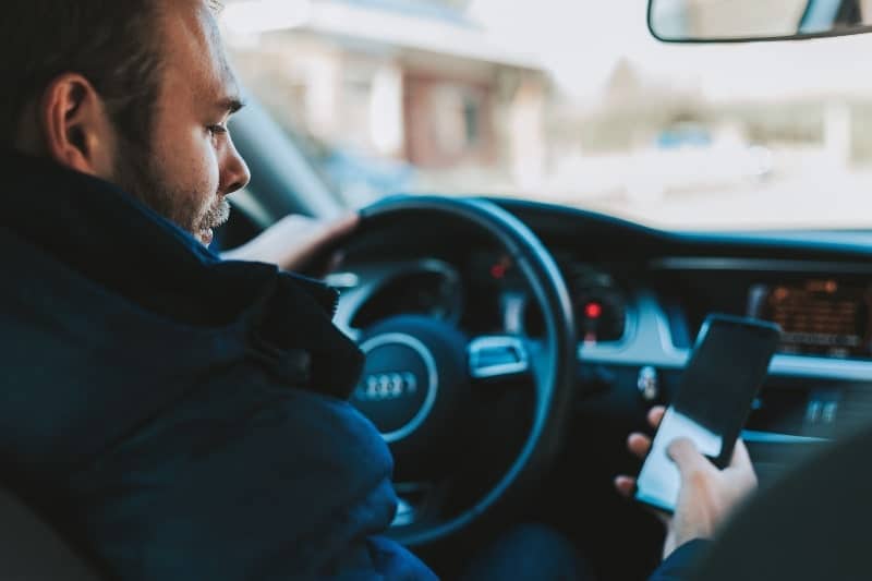 man driving and looking at his phone