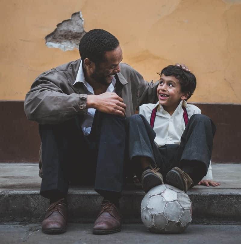 Man sitting with boy on step outside with ball | 2nd shift with a family