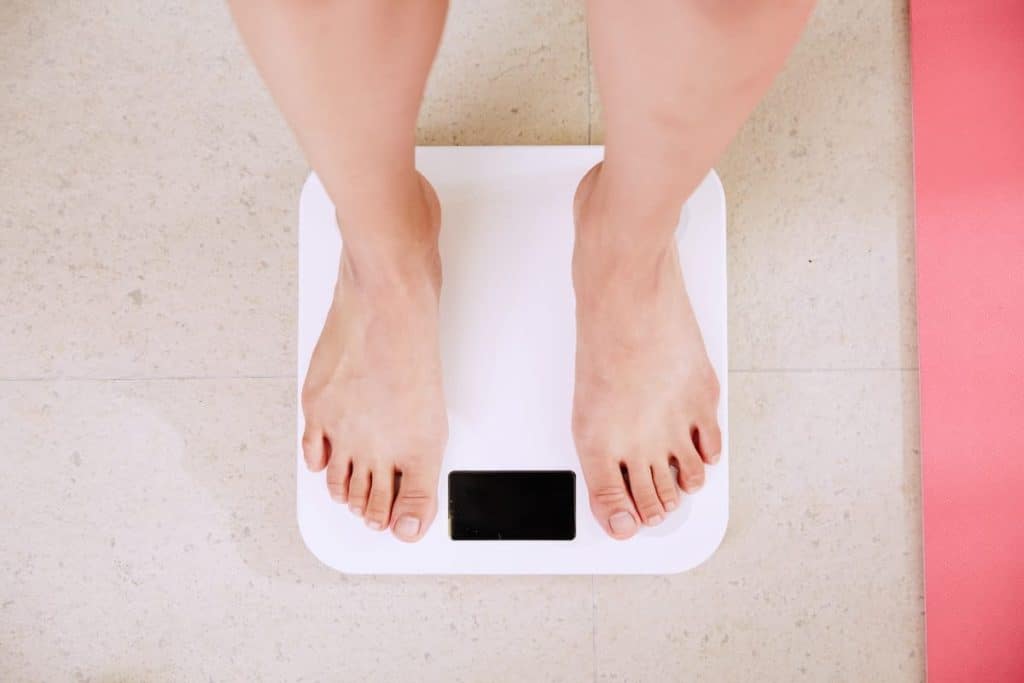 Standing on scales | Does Shift Work Make You Fat? 14 Tips to Avoid Weight Gain