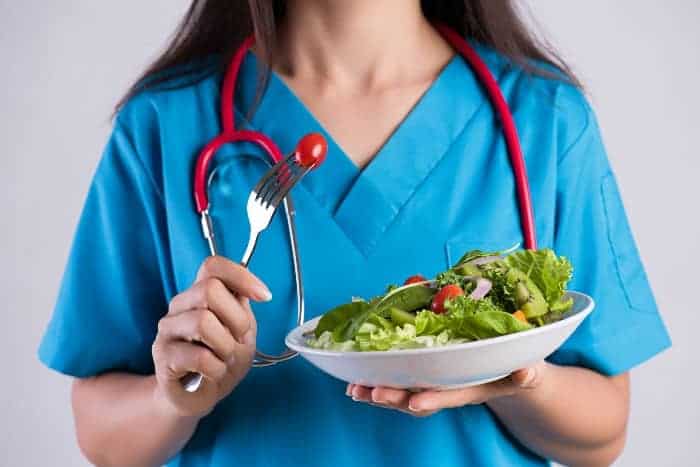 Women wearing scrubs holding salad bowl