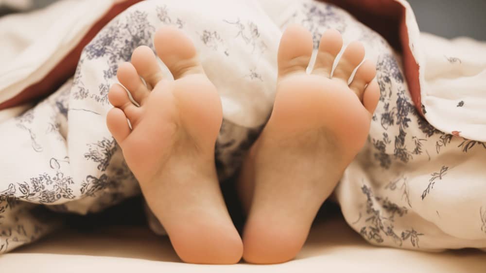 Two bare feet in bed